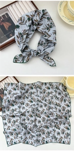 Detail view of square cotton linen scarf featuring olive branch prints and green hem