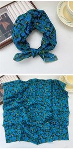 Close-up of blue floral cotton linen square scarf with yellow stitched edges and soft texture