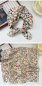 Macro detail of white floral silk scarf with vibrant orange flowers in a chic bow knot
