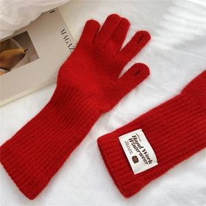 Detailed view of red knitted gloves with two-finger openings and a white decorative label
