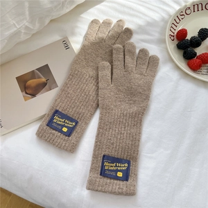 Close-up of brown knit gloves with reinforced cuffs and vintage textile brand label detail