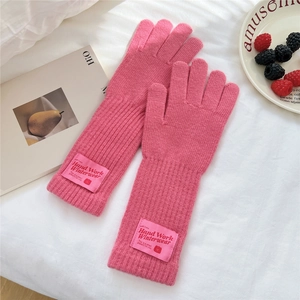 Detailed view of pink knitted mittens with ribbed texture and woven winterwear label