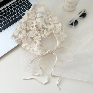 Detail of off-white lace triangle scarf with floral crochet patterns and wavy edges