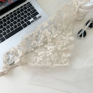Detailed view of floral embroidery lace scarf with wavy edges on a white work desk