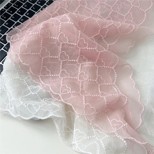 Détail de foulards en dentelle rose et blanc avec broderie cœur et bords festonnés