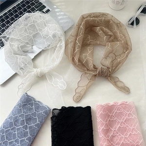 Foulard triangle en dentelle avec broderie cœur en plusieurs couleurs sur un bureau
