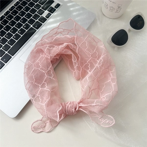 Détail d'une écharpe en dentelle rose avec motifs de cœurs et broderie fine