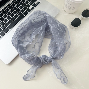 Détail d'un foulard triangle en dentelle à cœurs avec broderie Love et bord festonné