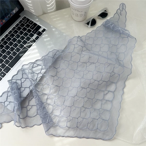 Détail d'un foulard en résille bleu clair avec broderie coeur et bords festonnés