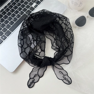 Détail du foulard triangle en dentelle noire avec motifs cœurs et broderie sur table