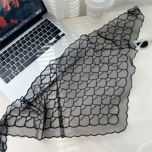 Détail d'un foulard triangle en dentelle noire à motifs de cœurs près d'un ordinateur