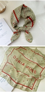 Detail of light green checkered scarf with red floral patterns and DORIA DORE lettering