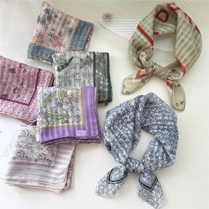 Flat lay of vintage floral cotton linen square scarves in soft pastel colors and bird prints