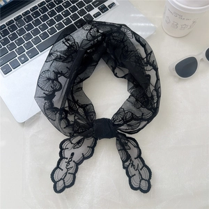 Close-up of black lace triangle scarf tied in a bow with delicate floral embroidery