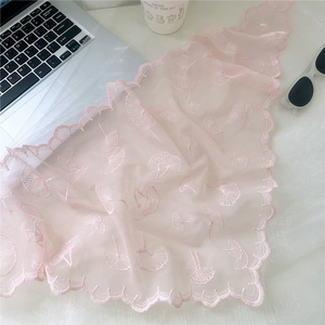 Close-up of light pink lace scarf with delicate ginkgo leaf embroidery and scalloped edges