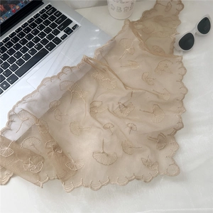 Detail of apricot lace scarf featuring intricate ginkgo leaf embroidery and wavy edges