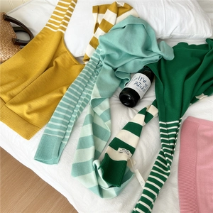 Flat lay of colorful striped knit camisoles in yellow, green and pink on white linen