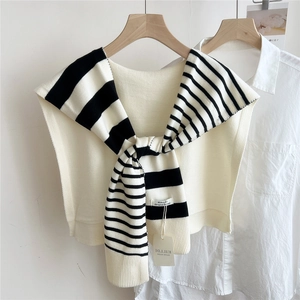 Detail of striped knit shawl with brand tag and soft texture on wooden hanger