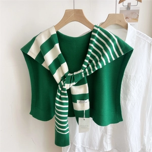 Detail of green and beige striped knitted shawl with woven label on white shirt