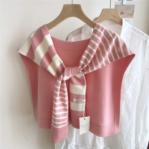 Detailed view of pink and white striped knitted shawl with branding label on white shirt