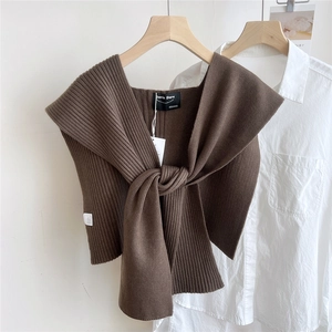 Detail of brown ribbed knit shawl with front tie knot over a white shirt background