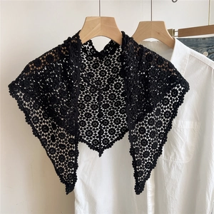 Detail of black crochet lace triangle shawl with intricate floral cut-outs on white shirt