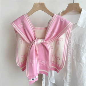 Detail of a pink and cream knit shawl featuring a sailor collar and a large front bow tie