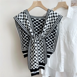 Detail of knit black and white honeycomb pattern shawl wrap over a crisp white shirt