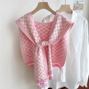 Detail of floral knit shawl with Pie apm label draped over a white shirt on hanger