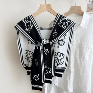 Detail of floral jacquard knit shawl with black and white stripes on a white shirt