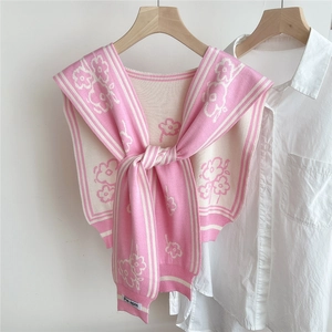 Close-up of pink and white floral knitted shawl with tie-front knot on a white shirt