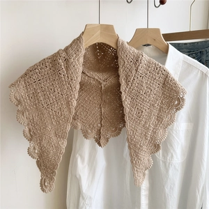 Handmade beige crochet triangle shawl with floral lace pattern on wooden hanger