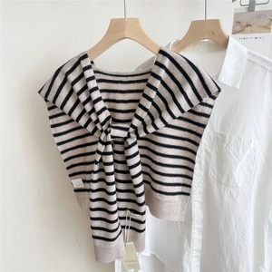 Detail of striped wool knit shawl with brand tags worn over a white shirt
