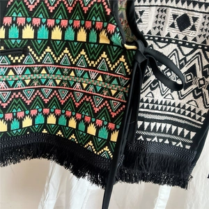 Close-up of ethnic woven vest shawl with geometric patterns and dense black tassels