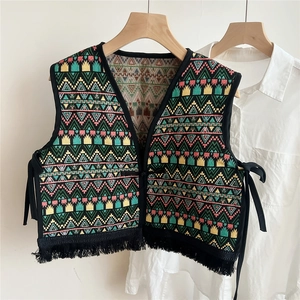 Close-up of ethnic woven vest shawl featuring colorful geometric patterns and black tassels