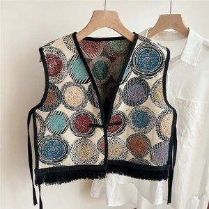 Close-up of ethnic jacquard vest showing colorful pattern, knotted closure, and fringe
