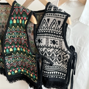 Ethnic knit vest with geometric patterns and fringe detail on wooden hangers