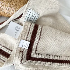 Close-up of knit fabric detail showing texture and brand label for decorative shawl