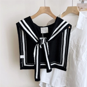 Detail of nautical black knit shawl with white stripes and tie closure on a white shirt