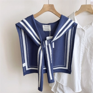 Detail of navy blue knit shawl with white stripes showing logo label on white shirt