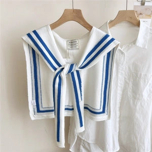 Detail of nautical navy-style knit shawl showing white fabric with blue stripes and brand tags