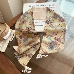 Detail of silk scarf with floral print and elegant pearl pendant on wooden background