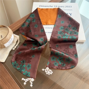 Close-up of floral silk scarf with orange lining and decorative pearl pendant tassels