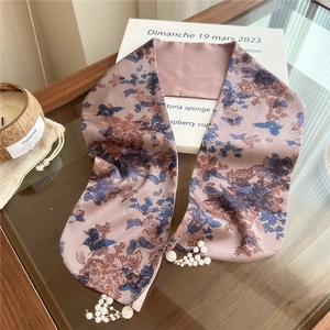 Detail of floral butterfly silk scarf featuring elegant pearl and metal chain tassels