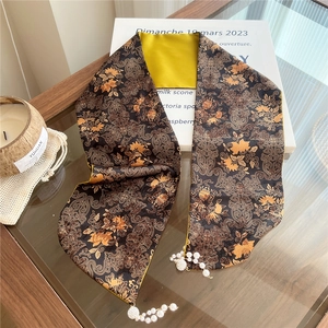 Detail of silk scarf with vintage floral patterns, golden satin reverse, and pearl charms