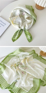 Détail d'un foulard en soie blanc avec bords rayés verts et motifs floraux en gros plan