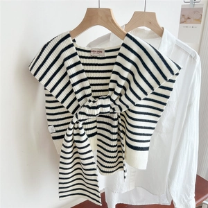 Detail of striped knit shawl with a unique knotted neckline design on a wooden hanger