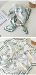 Détail d'un foulard en soie avec fond crème, imprimé feuilles vertes et bordure verte