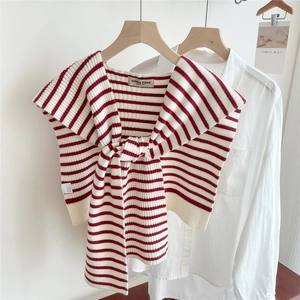 Close-up of red and white striped knit shawl with Doria Dore brand tag on white shirt