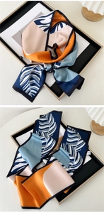 Close-up of a narrow silk scarf featuring stylish color-block and leaf vein patterns
